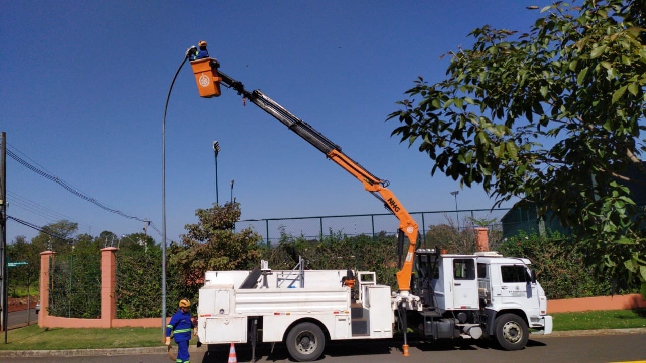 Equipe instalando luminária pública com caminhão cesto aéreo